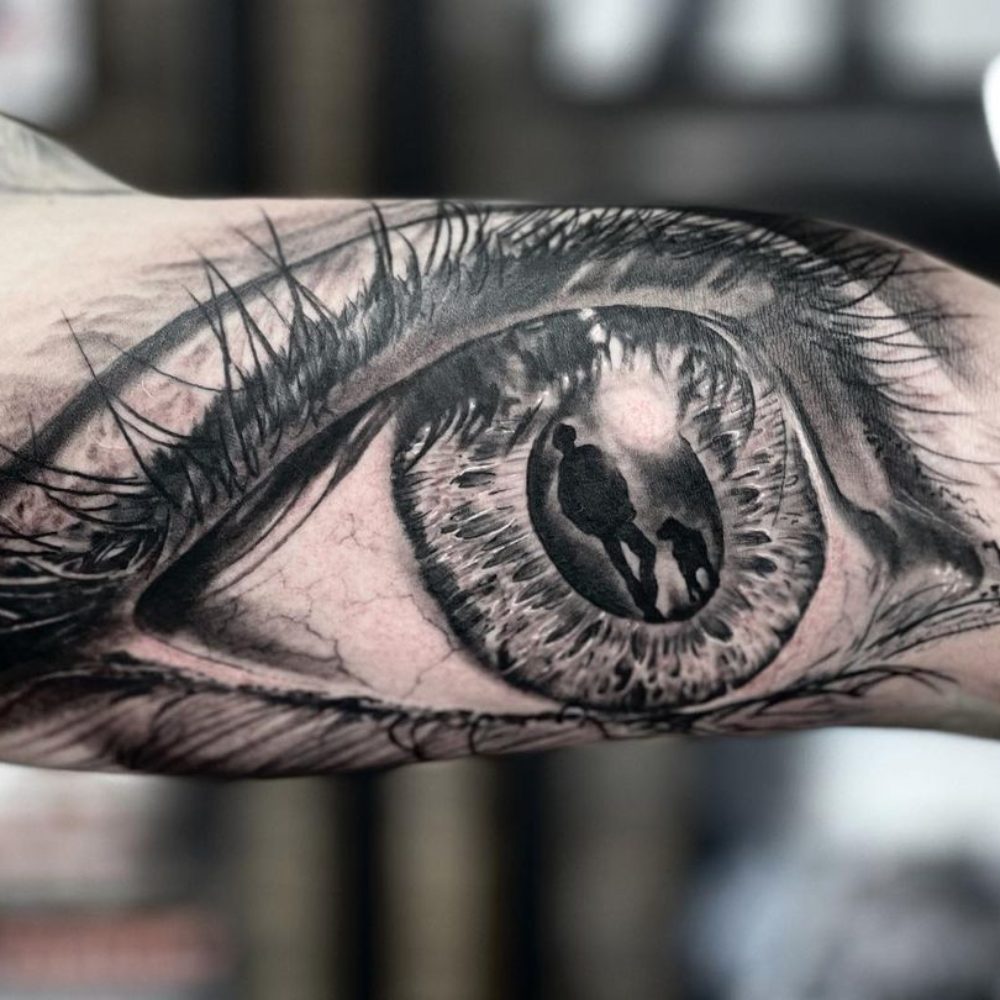 Bicep Tattoo eye with man and dog - Black Rose Tattoo Shop